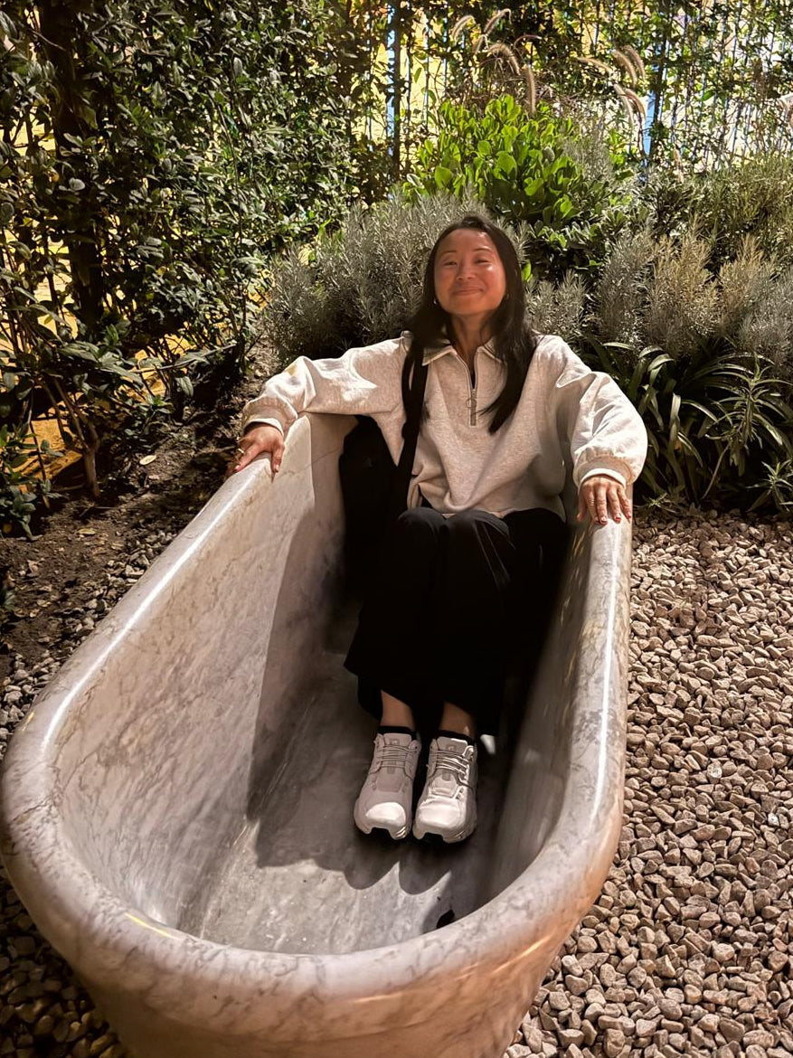 Person sitting inside a large stone planter in a garden setting